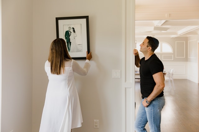couple hanging picture frame in house