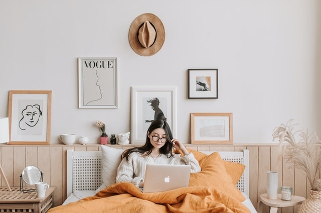 girl with frames on bedroom wall behind bed