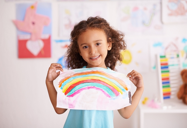girl holding up her painting of a rainbow