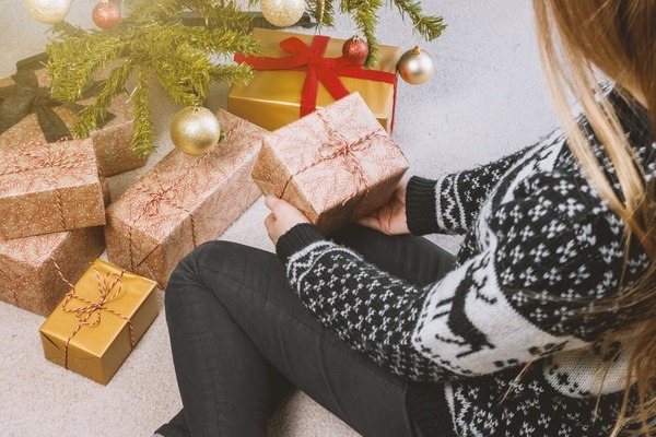woman choosing a gift box under a christmas tree
